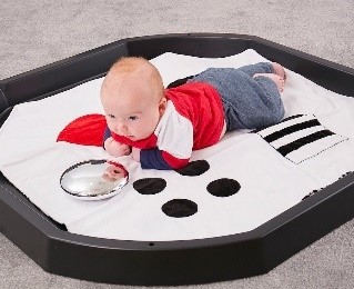 spelende baby op zwart eb witte mat in een Tuff Tray
