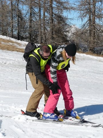 Voorbeel van een vorm van manuele begeleiding. De skileraar skiet in een
pizzapunt direct achter de vb-skier en drukt met zijn hand de knie van de
vb-skier naar binnen. 