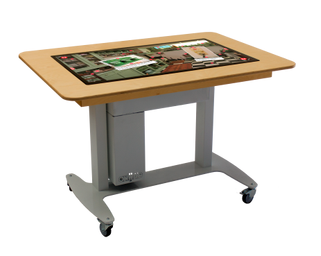 De Belevenistafel een tafel zo groot als een bureau. het midden is een groot
touchscreen zo groot als een flink televisiescherm. Om het scherm heen zit een
15 cm brede rand van hout waar je op kunt
leunen.