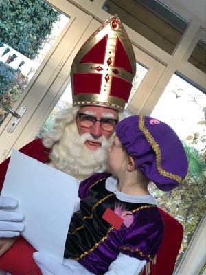 Sinterklaas leest een gedicht voor aan een jongetje
