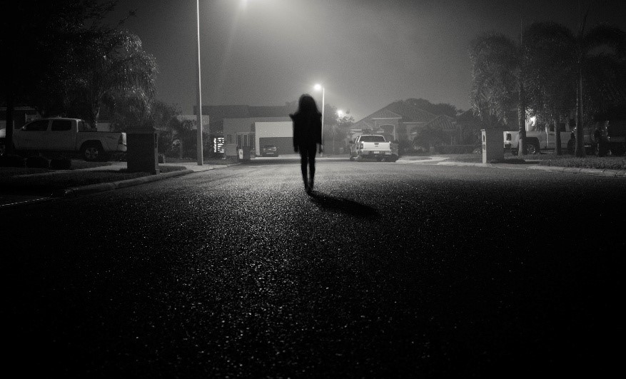 Vrouw die op straat loopt. Het is donker en er is straatverlichting. Bron:
Freepik, AI gegenereerde afbeelding.