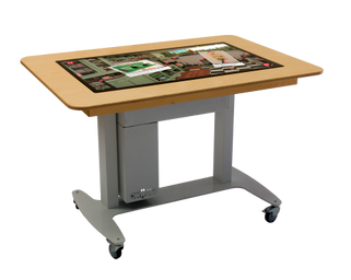 De Belevenistafel een tafel zo groot als een bureau. het midden is een groot
touchscreen zo groot als een flink televisiescherm. Om het scherm heen zit een
15 cm brede rand van hout waar je op kunt
leunen.