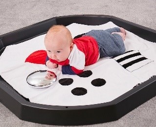 spelende baby op zwart eb witte mat in een Tuff Tray