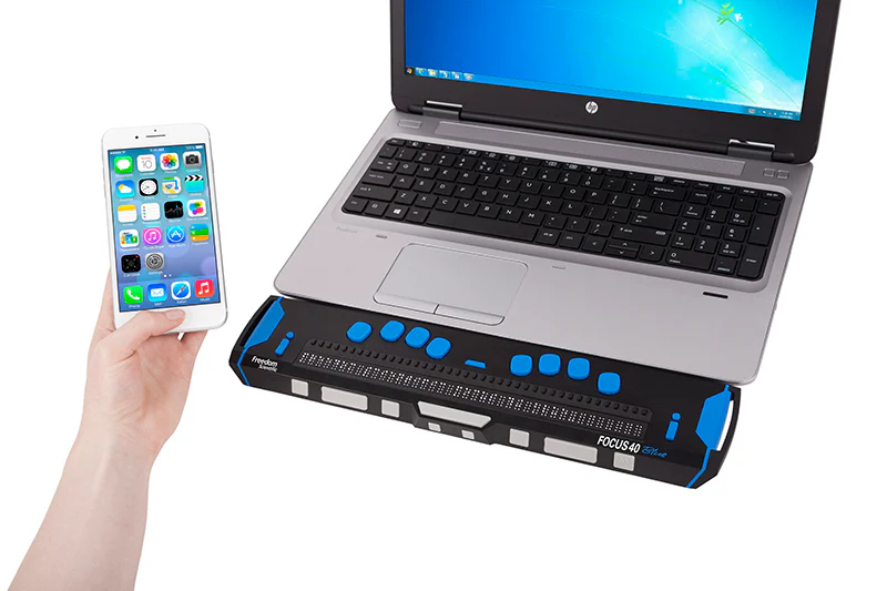 Een afbeelding van een brailleleesregel die voor een laptop staat met iemand
die een iPhone in de hand heeft. 