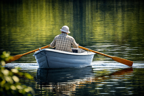 Man die in een roeiboot peddelt. De roeiboot van verlies is een metafoor die
je kan helpen met omgaan met verlies. Afbeelding gemaakt met behulp van
AI.